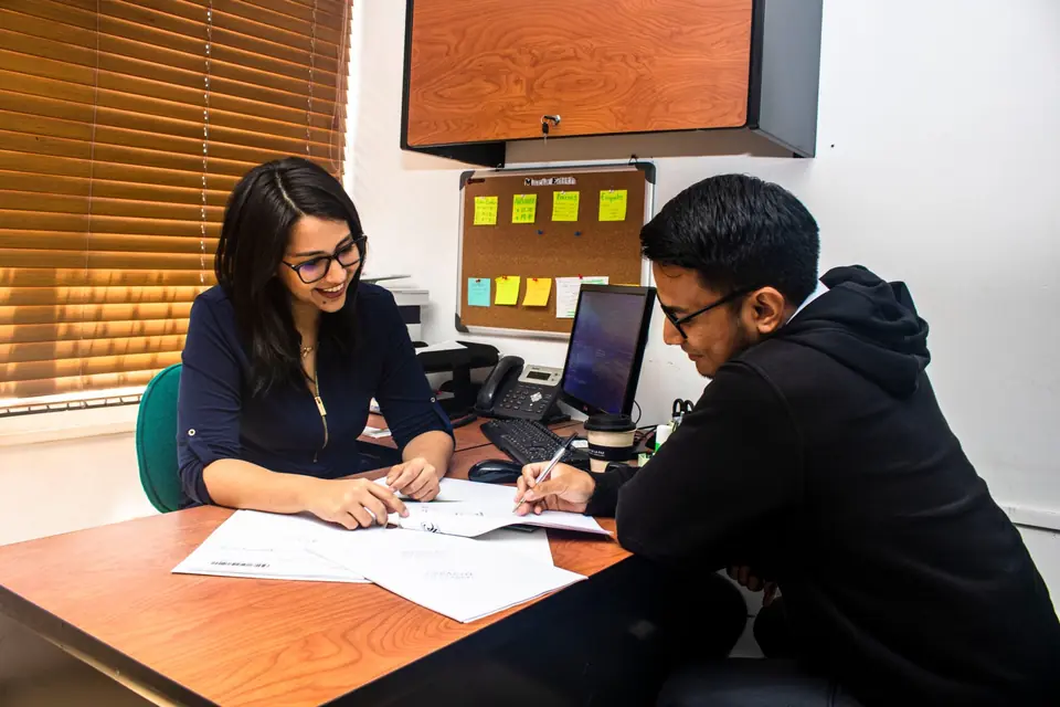 Asesora revisa documentos con un cliente en el escritorio