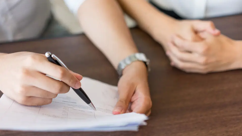 Dos personas firman documentos legales sobre una mesa