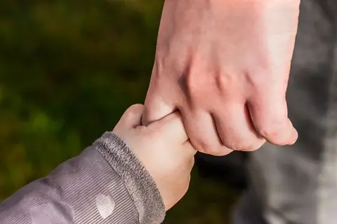 Mano de un niño sostiene la mano de un adulto